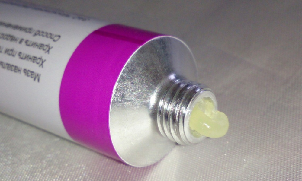 Ältere Frau im Badezimmer hält ein Cremeglas und lächelt ruhig